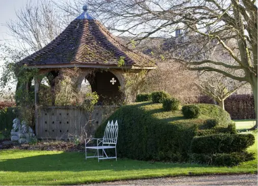  ??  ?? ABOVEThe gazebo, wreathed in climbers, including clematis ‘Blue Dancer’ and rose ‘Cécile Brunner’, offers a sheltered retreat in winter and a shady one on a hot day. A yew dragon, manicured by Simon and inspired by his and Kathy’s recent holiday in China, snakes around the gazebo