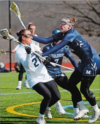  ?? DANA JENSEN/THE DAY ?? Connecticu­t College’s Hannah Lombard (21) fights to move the ball downfield against Middlebury’s Hayden Garrett (26) during Saturday’s game in New London. Middlebury, the top-ranked team in the national, rolled to a 16-5 victory over the Camels.