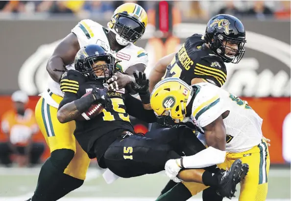  ?? MARK BLINCH/THE CANADIAN PRESS ?? The Hamilton Tiger-Cats’ Alex Green gets tackled by Eskimos Almondo Sewell, left, and Alex Bazzie last week.