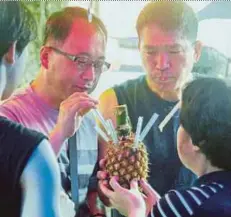  ?? PIC BY LANO LAN ?? Tourists enjoying pineapple juice at the Sunday Gaya Street market recently.