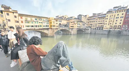  ?? ?? Tourist relax on the Lungarno near Ponte Vecchio in Florence.