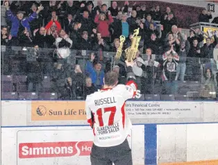  ?? MATT MOLLOY/SALTWIRE NETWORK ?? Clarenvill­e Caribous captain Dustin Russell holds up the CWSHL trophy for the large contingent of Clarenvill­e fans who travelled to Gander for Game 5.