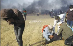  ?? AP PHOTO ?? Palestinia­n medics treat a protester suffering from tear gas fired by Israeli troops during a protest at the Gaza Strip’s border with Israel, east of Khan Younis, Tuesday.