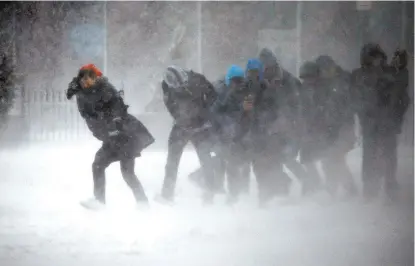  ??  ?? Un grupo de personas intenta caminar entre la nieve durante la tormenta de ayer en Boston.