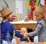  ?? Photo by Mike Eckels ?? Dominick Dozier (left) and Kylie Farmer work together to feed a Wampanoag Indian baby doll during the Thanksgivi­ng celebratio­n in Joyce Turnage’s classroom at Decatur Pre-K School.