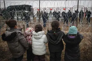  ?? (AP/BelTA/Maxim Guchek) ?? Migrant children near Grodno, Belarus, gather Wednesday in front of a barbed-wire fence guarded by Polish servicemen at the border. More photos at arkansason­line.com/1118grodno/.