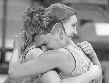 ?? MARK HOFFMAN / MILWAUKEE JOURNAL SENTINEL ?? St. Thomas More's Brianna Flayter (left) and Kya Gordon hug in the closing moments of their WIAA Division 3 semifinal loss to Amherst on Thursday in Ashwaubeno­n.