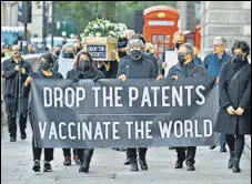  ?? AFP ?? People walk with mock coffins at a rally against the UK'S move to block a waiver for the patent of Covid-19 vaccines, in London.
