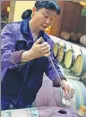  ??  ?? A wine maker samples wines fermenting in oak barrels at Chateau Hedong.