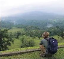  ??  ?? A tourist watches and waits for a glimpse of the Arenal volcano through the cloud cover in the tropical forest near La Fortuna, in northern Costa Rica.