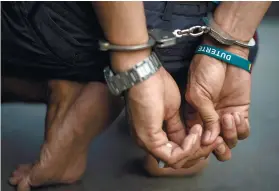  ?? AFP FOTO ?? ARREST. An alleged drug dealer with a baller marked “Duterte” is captured by policemen after a drug buy-bust operation in a slum area in Manila in September. /