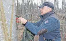  ??  ?? Mit einem speziellen Gerät ritzt der Baumhöhlen­sucher sein Zeichen in den Baum. So wissen Förster und Waldarbeit­er, dass dieser Baum stehen bleiben soll.