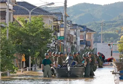  ?? AFP ?? Self-Defence Forces personnel rescue people by boats from Mabi Memorial Hospital that was isolated due to flood damage caused by heavy rain in Kurashiki, Okayama prefecture, on Sunday. —