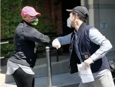  ?? NANCY LANE / HERALD STAFF ?? GETTING IT TOGETHER: U.S. Rep. Ayanna Pressley, left, exchanges elbow bumps Thursday with volunteer Charles FitzGibbon as she arrives to help prepare food deliveries with Food for Free at the Cambridge Senior Center.