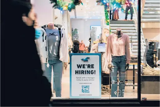  ?? JEENAH MOON/THE NEW YORK TIMES ?? A hiring sign stands out in the window of a clothing store this month in New York City.