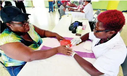  ??  ?? Dotty McKenzie (left) receives a manicure from Katleen Brown, a general beautician and therapist, at the Lions Club treat for senior citizens in Edgewater, Portmore, yesterday.