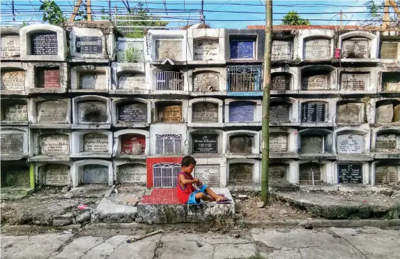  ?? BANAYNAL
ALDO NELBERT ?? A boy, unmindful of the annual Kalag-Kalag activity, uses the tombs as backdrop of his playground inside the Carreta Cemetery.