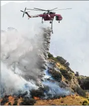 ?? MARK J. TERRILL / AP ?? A Skycrane helicopter drops water in Burbank, Calif., on Sunday. The blaze chewed through brush-covered mountains, prompting evacuation orders for homes in Los Angeles, Burbank and Glendale.