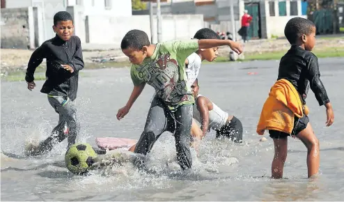  ??  ?? Boys play football on a flooded field in Mitchells Plain yesterday, after Cape Town’s heaviest rain of the year so far. More than 70mm was recorded in parts of the city on Friday morning. Dam levels, which were already higher than at this time last...