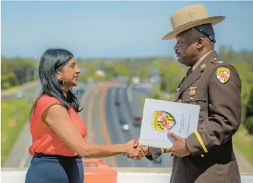  ?? ?? Maryland Lt. Gov. Aruna Miller shakes hands with Roland Butler Jr., colonel with the Maryland State Police, as the pair frame the work zone in the background, the site where six road workers were killed last year in the median of the Baltimore Beltway. Maryland and MDOT officials held a National Work Zone Awareness Week kickoff on the westbound I-70 bridge over I-695.