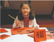  ?? Dick Evans / Heyday Books ?? Yuhan Chen, 6, perfects her calligraph­y at a Chinese New Year event at the Chinese Culture Center.