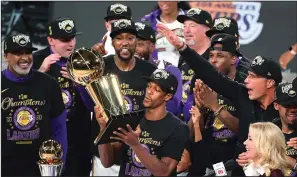  ?? WALLY SKALIJ/LOS ANGELES TIMES ?? Above: The Lakers' Rajon Rondo takes the trophy after the Lakers defeated the Miami Heat to win the NBA Finals on Sunday in Orlando, Fla. Below: The Lakers' LeBron James, left, and Anthony Davis celebrate in the closing seconds.