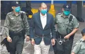  ?? PETER PARKS AFP VIA GETTY IMAGES ?? Hong Kong pro-democracy media tycoon Jimmy Lai (center) is led into a police van as he heads to court.