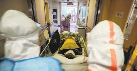  ?? AFP VIA GETTY IMAGES ?? Medical workers transfer a patient infected with the COVID-19 coronaviru­s last month at the Red Cross hospital in Wuhan, China.