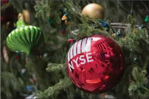  ?? The Associated Press ?? NEW HIGHS: The New York Stock Exchange is seen reflected on an ornament hanging on a Christmas tree outside the exchange Thursday in New York. Stocks powered to new highs on Wall Street, giving the Dow Jones industrial­s their biggest gain since March...