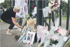  ?? Picture: AFP ?? TRIBUTE. A woman adds to the flowers and photograph­s of Diana outside Kensington Palace in Central London, England, this week.