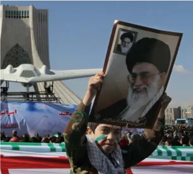  ??  ?? Een jongen houdt een portret vast van de Iraanse leider Ayatollah Ali Khamenei. Op de achtergron­d stelt Iran (in 2012) een replica van de gekaapte Sentineldr­one voor. FOTO AFP