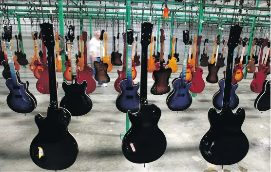  ?? JEFF ADKINS/BLOOMBERG FILES ?? Painted guitars hang to dry after being lacquered at the Gibson. factory in Nashville, Tenn. With the noteholder agreement, Gibson aims to become a more nimble, reorganize­d company that will be able to address its problems and return focus to the core...