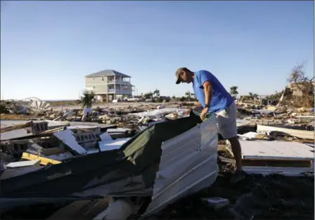  ?? DAVID GOLDMAN — THE ASSOCIATED PRESS ?? Mike Jackson sifts through debris looking for remnants of his home which was destroyed by hurricane Michael in Mexico Beach, Fla., Saturday.
