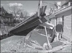  ?? ASSOCIATED PRESS ?? A man walks by a piece of the Rockaways boardwalk that was washed into the street, alongside a small car that was destroyed by Sandy as storm cleanup continued in the Rockaways neighborho­od of New York.