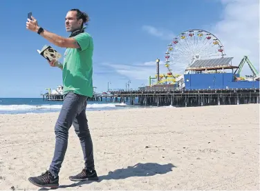  ?? AFP ?? Adam Duford, owner of Surf City Tours, describes iconic sites in Santa Monica, California as part of a ‘virtual tour’ via his Instagram feed.