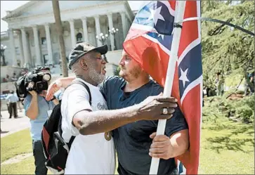  ?? JOE RAEDLE/GETTY ?? A flag opponent hugs a backer to show mutual respect despite their difference­s at protests at the South Carolina Capitol.