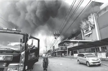  ?? AGENCE FRANCE PRESSE FILE VIA PHILSTAR.COM ?? This photo on December 23 shows a firefighte­r standing in front of the burning shopping mall in Davao City where 38 people died.