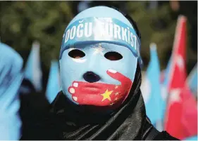  ?? — Reuters ?? A demonstrat­or wears a mask as she attends a protest against China in front of the Chinese Consulate in Istanbul, Turkey.