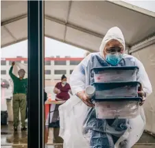  ?? — AFP photo ?? An Xpress Covid Testing medical assistant shelters equipment from the rain in Houston, Texas.