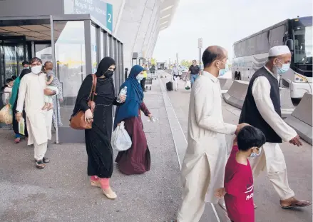  ?? GEMUNU AMARASINGH­E/AP ?? Families evacuated from Afghanista­n walk to board a bus after arriving at Virginia’s Dulles Internatio­nal Airport on Tuesday.