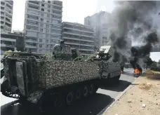  ?? Getty; AP ?? Terrified residents are helped away from the Palace of Justice neighbourh­ood in Beirut, top, as Lebanese soldiers watch burning barricades manned by Shiite groups