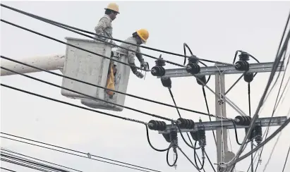  ?? WICHAN CHAROENKIA­TPAKUL ?? Workers fix a power line in Samut Prakan. The PEA sets to launch smart grid projects, firstly in five major cities, all are tourism destinatio­ns.