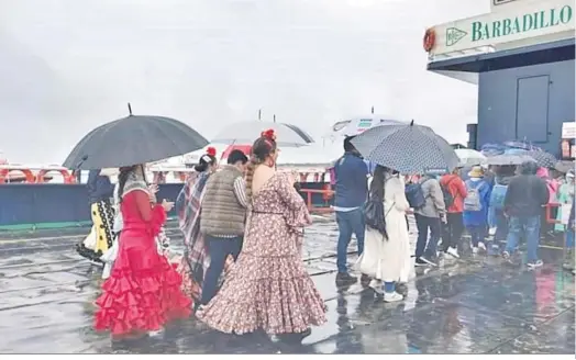  ?? ?? Peregrinos de la Hermandad de Chipiona, ayer con paraguas en una de las barcazas que trasladan a los romeros desde Bajo de Guía hasta Doñana.