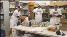  ?? STAFF PHOTO BY TIFFANY WATSON ?? Southern Maryland Blue Crabs players Zach Wilson, Shaun Garceau and Cody Eppley make food bags at the Charles County Children’s Aid Society in Waldorf last Thursday.