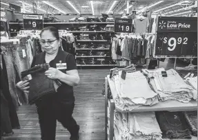  ?? TIMOTHY FADEK / GETTY IMAGES ?? An employee arranges clothing at a Walmart Inc store in Secaucus, New Jersey. Walmart is expected to be hit if a trade war starts.