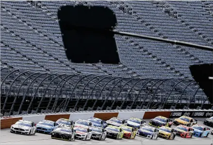  ?? PHOTOS BY BRYNN ANDERSON / AP ?? Cars approach the starting line before taking the green flag in front of empty stands to start the Cup Series race Sunday at Darlington Raceway in South Carolina. Race winner Kevin Harvick said the complete lack of fans was jarring.