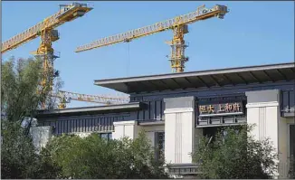  ?? ?? Constructi­on cranes stand near an Evergrande new housing developmen­t showroom office building in Beijing on Sept. 22, 2021. China’s central bank said that financial risks from China Evergrande Group’s debt problems are ‘controllab­le’ and unlikely to spill over. (AP)
