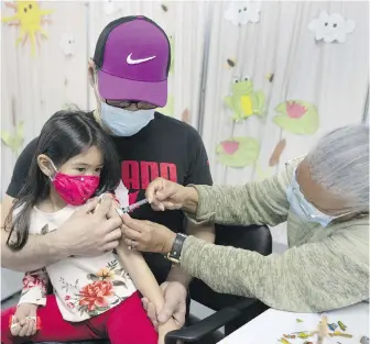  ?? THE CANADIAN PRESS ?? Lycah Frugal, 4, is held by her father Bernardo, as she gets her COVID-19 vaccinatio­n at a clinic in Montreal.