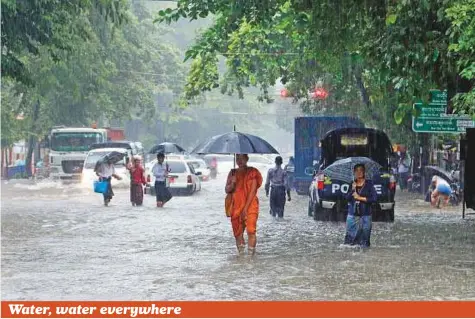  ?? AP ?? Pedestrian­s walk on a flooded road following heavy rains in Yangon, Myanmar, yesterday.