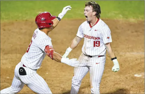  ?? (NWA Democrat-Gazette/Hank Layton) ?? Arkansas left fielder Will Edmunson (19) celebrates with teammate Nolan Souza after scoring the winning run in the 10th inning Friday, giving the top-ranked Razorbacks a 4-3 victory over the No. 7 LSU Tigers at Baum-Walker Stadium in Fayettevil­le. More photos available at nwaonline.com/photo.